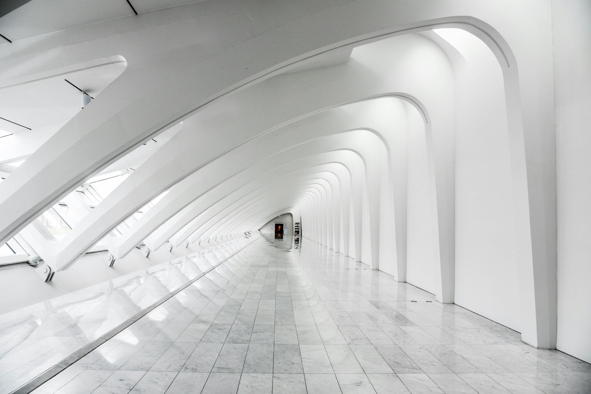 Long white arched corridor with a polished stone floor